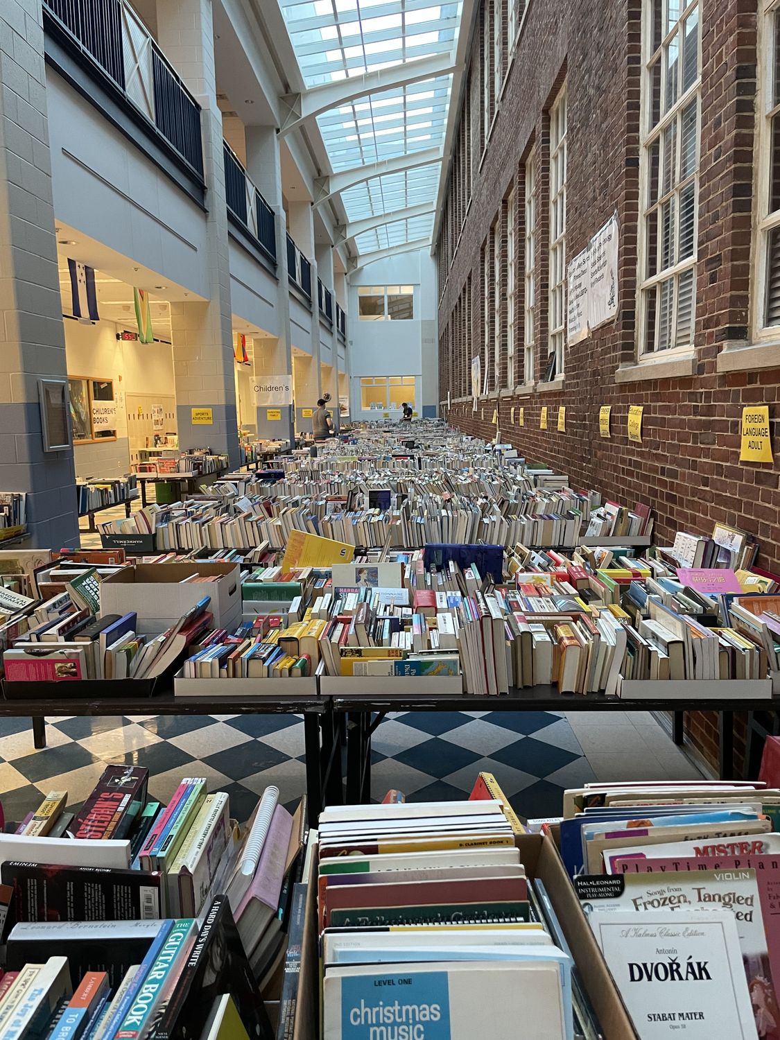 The Art Atrium during the sale, with rows of tables stretching down a skylit hallway, every one covered in books.