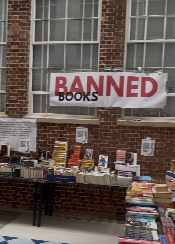 A large banner reading Banned Books hanging above a display table of frequently challenged titles.