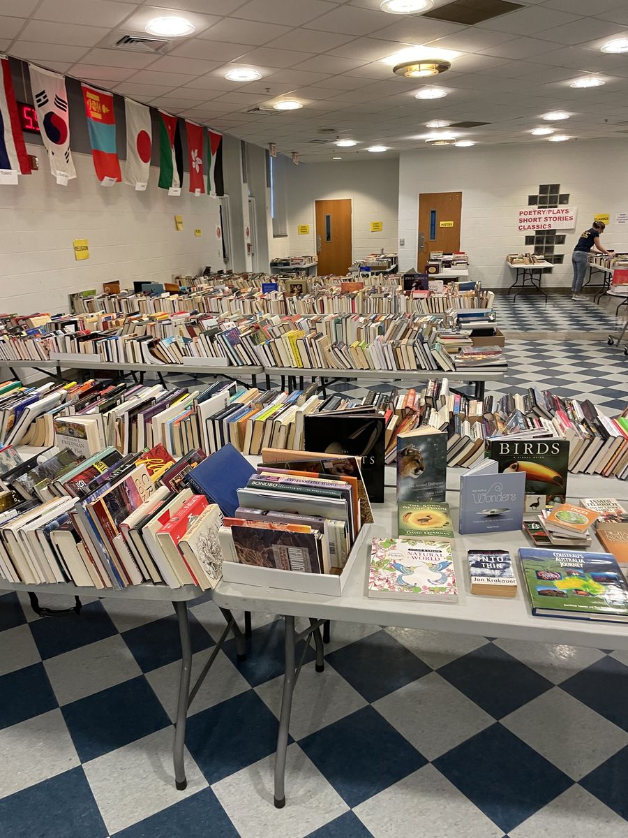 Rows of tables of books beneath hanging international flags, with signs for Poetry, Plays, Short Stories and Classics.